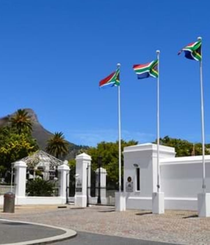 South African flags flying in front of official white architecture in Cape Town